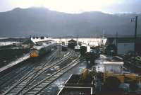 A train for Inverness stands at the platform at Kyle of Lochalsh on a wet Saturday afternoon in November 1982. Freight activities (including coal in the foreground) still survive at this point in time.<br><br>[Frank Spaven Collection (Courtesy David Spaven) 20/11/1982]
