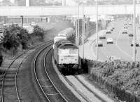 A class 47 accelerates a freight consisting of various new motor vehicles away from Dundee in the summer of 1981. The train is heading east towards Broughty Ferry along the section of line running between the A92 and the docks.<br><br>[John Furnevel 11/08/1981]