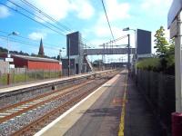 Platform view south at Lockerbie on 3 August, with the towers of the station footbridge and associated lifts, installed in 2008, now competing with the Gothic spire of St Cuthberts Church on Bridge Street, built 136 years earlier.<br><br>[Andrew Wilson 03/08/2011]