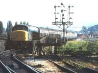 A 'Peak' rumbles over the bridge on the approach to Exeter St Davids station, coming out of the sun with a Paignton - Leeds train in the summer of 1985.<br><br>[Ian Dinmore //1985]