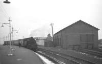 A train for Glasgow stands at Farlie Pier station on a dismal looking Monday 25 February 1963. On the right is the former 2-road locomotive shed - built in 1918 to replace a burned-down 1882 timber original. The shed had closed in 1930 but was later acquired for boat storage and repair by a local boatbuilder. (The original roof featured a long smoke vent which had been removed in a subsequent re-roofing.) The building was finally demolished in 1987. Fairlie Pier station itself was officially closed in October 1971, although the last train visited the station in July 1972.<br><br>[R Sillitto/A Renfrew Collection (Courtesy Bruce McCartney) 25/02/1963]