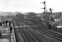 Looking east from the station footbridge at Haltwhistle on a grey 27 March 1976. The Alston branch curves away on the climb towards the viaduct over the South Tyne on the right, while a healthy complement of passengers waits on the staggered eastbound platform for the next service to Newcastle.<br><br>[Bill Jamieson 27/03/1976]