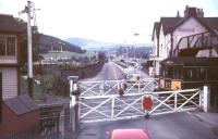 View from the top deck of a bus stopped at Conwy Road level crossing in the 1960s looking south west towards Conwy Castle. A Rhyl bound DMU off the Llandudno branch is about to run over the crossing and will shortly arrive at Llandudno Junction station off picture to the left. The scene no longer exists, with the level crossing now replaced by a flyover, the signal box long gone, the pub on the right (the 'Maelgwyn') demolished etc ..etc. [see image 36849]<br><br>[Ian Dinmore //]