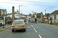 A reminder of the days of the manual level crossing gates at Hythe station, Colchester, in 1978, when rush hour cars and buses could be substantially delayed by a succession of trains. The later provision of lifting barriers and the building of a new road bridge nearby eventually eased the problem. The crossing keeper used to get very irate with impatient drivers following nose to tail processions over the crossing preventing him from closing the gates.<br><br>[Mark Dufton 18/09/1978]