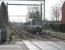 Metrolink 1006 leads a four car formation off the double track section from Altrincham and over the level crossing into Navigation Road. At the same point the Network Rail single track branches out to two lines again but on this side the overhead catenary was removed in 1992. With a tram in each direction every six minutes plus passenger and freight trains the barriers at this crossing are kept very busy.<br><br>[Mark Bartlett 08/03/2012]