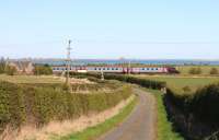 View east at Low Moor Crossing, Fenham le Moor, Northumberland on 5th April 2012. An up CrossCountry service runs through the crossing, with the holy island of Lindisfarne in the background. <br><br>[Brian Taylor 05/04/2012]