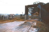 The bulk discharge facility at the end of the long private siding that ran from Alness station to Dalmore distillery, seen here in 1974, by which time the siding had already been closed. The old signal box in the background is the relocated Alness box, with the station sidings by this time being controlled by a ground frame.<br><br>[David Spaven //1974]