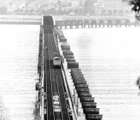 A Type 2 crosses the Tay Bridge with a Dundee - Edinburgh train in 1983, while two figures walk along the down line. The piers of the ill-fated original bridge still stand alongside.<br><br><br>
 <I>Beautiful Railway Bridge of the Silv'ry Tay!<br><br>
 Alas! I am very sorry to say<br><br>
 That ninety lives have been taken away<br><br>
 On the last Sabbath day of 1879,<br><br>
 Which will be remember'd for a very long time.</I><br><br><br>
William McGonagall (1825-1902)<br><br>[John Furnevel 05/04/1983]