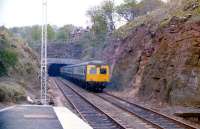 A train for Largs disappears 'wrong line' into the tunnel at Fairlie in 1986, with the down line out of use pending electrification. Once the layout on the branch has been 'rationalised', the up line will be lifted and masts erected, with the down line and platform becoming bi-directional. <br>
<br><br>[Colin Miller //1986]