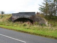 Looking west across the A6105 at  Greenlaw on 6 October 2012 to the long abandoned bridge that once carried the road over the Berwickshire Railway. The chimneys of the former station, now a private residence, can be seen rising above the embankment. Greenlaw station closed in 1948 along with the route east towards Duns, although the line west to Ravenswood Junction remained open until 1965 [see image 34992].<br><br>[John Furnevel 06/10/2012]