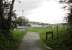 The site of the Campbeltown and Machrihanish carriage and loco sheds, now an open space, was just at the top of the steep bank from the quayside. This is the modern day view looking west from the end of the deep cutting with its trackbed footpath. The houses in the distance are built over the old line. [See image 33469] for a map showing the cutting and sheds in 1921.<br><br>[Mark Bartlett 13/10/2012]
