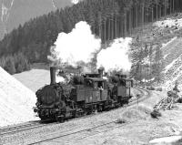 Having taken the 11.20 half load of iron ore from Erzberg to the summit station at Prbichl, conventional chimneyed 0-6-2RT No. 97.207 and Giesl fitted No. 97203 drift downhill at Feistawiese on 15 April 1976 on their way to pick up the second portion. <br><br>[Bill Jamieson 15/04/1976]