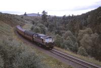 Just north of Grantown-on-Spey, a BRCW Type 2 hauled train drifts down the gradient from Dava Summit, not long after the 1958 start of dieselisation in the Highlands. <br><br>[Peter Oliver Collection (Courtesy David Spaven) //1958]