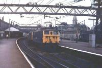 A double-headed eastbound freight trundles through Guide Bridge in 1978 with 76030 in the lead. The <I>Tommies</I> are on the now lifted tracks while over on the right, Class 40 40134 waits for a green signal with a Ford container train. The buildings in this view, and the footbridge, have since disappeared and the area between the platforms has been filled in leaving only the other two lines still active. <br><br>[Mark Bartlett //1978]