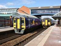 On the left a Class 158 calls at Barnsley Interchange on 12 March 2013 with a Sheffield to York fast service. On the right the Class 150 is on the Huddersfield to Sheffield via Penistone service. A smart station building with covered footbridge which links direct into the bus station on the left.<br><br>[John McIntyre 12/03/2013]