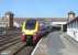 Virgin Trains 5 car Voyager 221102 during its 68 minute layover at Holyhead before becoming the lead set for the 13.58 return service to London. Note the graphics on the modern footbridge made redundant when Stena moved the port facilities to the seaward end of the station. <br><br>[David Pesterfield 16/04/2013]