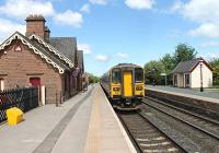 Passing the distinctive red sandstone station building, now a tea room, a Leeds to Carlisle service pulls away from Langwathby in June 2013. As with many S&C services the train is formed of a class 158/153 combination.<br><br>[Mark Bartlett 05/06/2013]