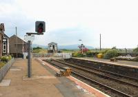 Looking south towards Ravenglass at Drigg station in July 2013. The mechanical signalbox controls colour light signals that protect the level crossing and form a block section between Sellafield and Bootle boxes. Note the steps on both low platforms to allow easier access to the trains. Presumably these will in due course be replaced by the new <I>Harrington Humps</I> as at Seascale, the next station north of here. <br><br>[Mark Bartlett 27/07/2013]