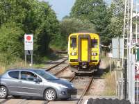 The driver of 153323 reaches out from his cab to operate the crossing barriers in order to enter Llandovery station with the 16.37 <I>Heart of Wales</I> line service forward to Swansea<br><br>[David Pesterfield 01/08/2013]