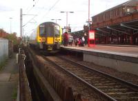 The unusual sight of a passenger train on platform 6 in Rugby (a 350 destined for Euston). As the station is run by Virgin Trains, there is a gent in a red shirt helping London Midland passengers. The path on the left leads from the station underpass to a multi-storey car park.<br><br>[Ken Strachan 30/08/2013]
