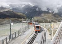 A pair of twin car sets are climbing the last few yards into the summit station at Gornergrat. The height difference between the 10,132ft summit (the highest open air station in Europe) and the Zermatt terminus is 4820 ft, achieved in less than 10km of rack railway climbing. <br><br>[Mark Bartlett 12/09/2013]