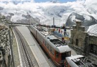 With the Gorner Glacier ahead a four car train draws to a halt in Gornergrat (10132ft). The station opened in 1898 and has a year round service at basic half hourly intervals but the line can operate more frequent trains at busy times. A hotel and observatory are just off picture to the left.<br><br>[Mark Bartlett 12/09/2013]
