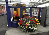 The 10.27 service to Glasgow Central stands in the bay at Kilmarnock station on 16 October behind another of the colourful planters maintained by the local Hurlford Gardening Club.<br><br>[John Yellowlees 16/10/2013]