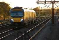 Heading west into the setting sun on 9 October 2013, a TransPennine service from Cleethorpes to Manchester Airport leaves Barnetby, with the array of semaphore signals standing guard over the approach to Wrawby Junction.<br><br>[John McIntyre 09/10/2013]