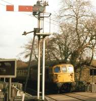 A fine spring Saturday morning in April 1985 sees a class 33 with an Exeter - Barnstaple train draw slowly into Eggesford station over the level crossing.<br><br>[John Stanford /04/1985]