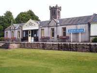 A platform side view of the northern section of Aberlour station in June 2013, complete with its BR Scottish Region blue wooden running in board. The neo-Norman tower of Aberlour Parish Church rises beyond the station roof.<br><br>[David Pesterfield 24/06/2013]