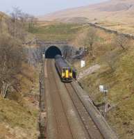A Northern service from Carlisle to Leeds exits Blea Moor Tunnel on 29 March 2014. The course of the tunnel can be seen on the hillside with spoil heaps and air shafts providing the clues.<br><br>[John McIntyre 29/03/2014]