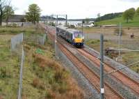 Shortly after passing through Caldercruix and skirting Hillend reservoir, 334013 is about to run past the remains of the demolished Forrestfield station. The train is the 11.27 Milngavie - Edinburgh, which runs non-stop between Drumgelloch and Bathgate. The cyclists on the right are using the cycle path/walkway built to replace that reclaimed by the reopened railway. [See image 9671]<br><br>[John Furnevel 08/05/2014]