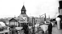 The original Victorian pier buildings at Rothesay in the 1950s with the two-funneled <I>Queen Mary II</I> alongside. She gained a new larger single funnel when re-boilered and converted to oil-burning in 1957. [Old family photograph]<br>
<br><br>[Colin Miller Collection //]