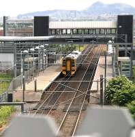 View east from a city bound Edinburgh tram on the flyover crossing the E&G at Edinburgh Park on 11 June 2014. The train at the platform is the 10.58 Dunblane - Edinburgh.<br><br>[John Furnevel 11/06/2014]