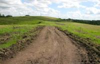 The trackbed of the former Tannochside Branch of the Caledonian Railway, looking east from near the site of the Cutty Sark bridge in June 2014. Vegetation has been cleared and the solum is in use as an access route for the M8 Baillieston extension advance works.<br><br>[Colin McDonald 11/06/2014]