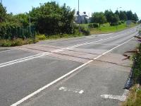 This well maintained level crossing is immediately north of the former Amlwch station site and runs across the A5025. It is on the section of line that continued to the former Associated Octel plant on the cliff top west of Amlwch Port. View east in July 2014.<br><br>[David Pesterfield 24/07/2014]