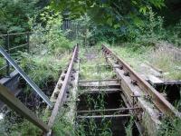 Looking north along the fenced off rail overbridge across the River Cefni, located a short distance from the former Llangefni station, showing the deteriorating condition of the rail supporting waybeams and missing section of base timber and sleepers.<br><br>[David Pesterfield 23/07/2014]