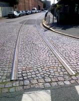 A disused industrial siding in the North Eastern Paris suburb of Pantin in August 2014. A turnout can just be seen in front of the approaching car. The cobblestones are laid out in an attractive pattern.<br><br>[Ken Strachan 05/08/2014]