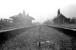 The derelict station at Earby, Lancashire, closed in February 1970. Photograph taken in October 1976 looking south west over the former Salterforth Road level crossing towards Colne. [See image 39293] [Ref query 13081]<br><br>[Ewan Crawford Collection 14/10/1976]