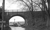 Undated photograph of the bridge at Caddon Mill, just west of Clovenfords, that carried the Peebles branch over the A72, the third of five crossings of the railway and the A72 between Galashiels and Thornielee. The Austin 12/6 (with thanks to Ken Strachan) registration LS 3456 parked in the entrance to Caddon Mill (the view is west), probably belonged to the photographer who, as an employee of Selkirk County Council, would have been well placed to obtain a distinctive number for his new car.<br><br>[Bill Jamieson Collection //]