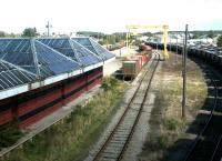 View northeast from the road bridge over Elgin East station and Yard in September 2004. The former locomotive shed, now in use as commercial premises, stands in the background beyond the stored wagons.<br><br>[John Furnevel 12/09/2004]