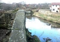 Looking north in 2003 over the remains of the southernmost of the two former railway bridges which spanned the Water of Leith between Powderhall and Bonnington stations [see image 3176].<br><br>[John Furnevel 10/03/2003]