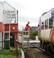 An Inverness service picks up the token for Forres at Elgin West Signalbox. This is the only operational signalbox in Elgin now and is the furthest north signalbox in the UK.<br><br>[Ewan Crawford //2005]