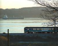 A West Highland Line train heading east from Cardross passes a ship sailing down the Clyde<br><br>[Beth Crawford 18/11/2005]