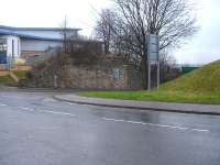A substantial stone bridge abutment on the north side of Old Mill Lane, Barnsley, on the line connecting Court House Junction, beyond the building ahead, to Court House Station, behind the camera. A short isolated section of south side approach embankment stands on the right <br><br>[David Pesterfield 16/02/2015]
