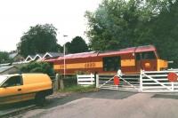 The driver of EWS 60001 chats to a colleague operating the level crossing gates on the branch line serving Denby opencast loading point in Derbyshire in July 1997. The roof of the former Coxbench station is visible above the rear of the loco and the leading wagon. <br><br>[David Pesterfield 15/07/1997]