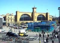 The market stalls have moved in and the blue mesh is back around the Kings Cross underground entrance building on 15 April 2015, the warmest day of the year so far. View from the eastern end of the St Pancras Station terrace.<br><br>[Andrew Wilson 15/04/2015]