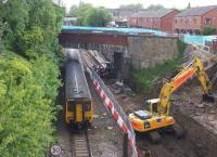 Looking towards Farnworth station from above the tunnel portals on 2 June 2015 as a Hazel Grove to Preston service passes. On the right the excavator is removing soil from the new track alignment.<br><br>[John McIntyre 02/06/2015]