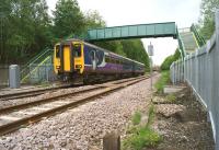 Northern 156451 passes under the relatively new footbridge to the north of Kearsley station on 2 June 2015. The footbridge replaced the foot crossing, the remains of which are in the centre foreground (a wooden post from the wicket gate and the concrete ramp) in March 2015.<br><br>[John McIntyre 02/06/2015]