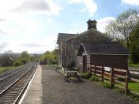 Platform view west through Redmire Station on the Wensleydale Railway in May 2015, showing the lengthy run round loop on the left and the loading sidings for military vehicles to and from Catterick Garrison on the right beyond the platform end. <br><br>[David Pesterfield 25/05/2015]